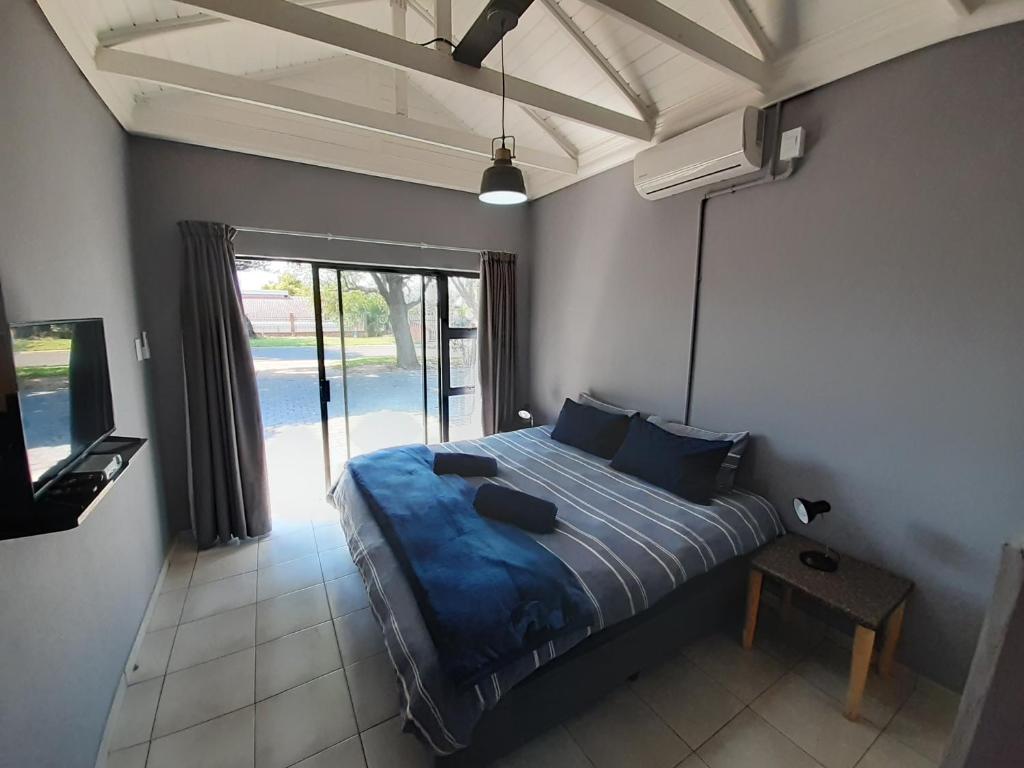 1 dormitorio con 1 cama con sábanas azules y TV en Honeysuckle Manor, en Richards Bay