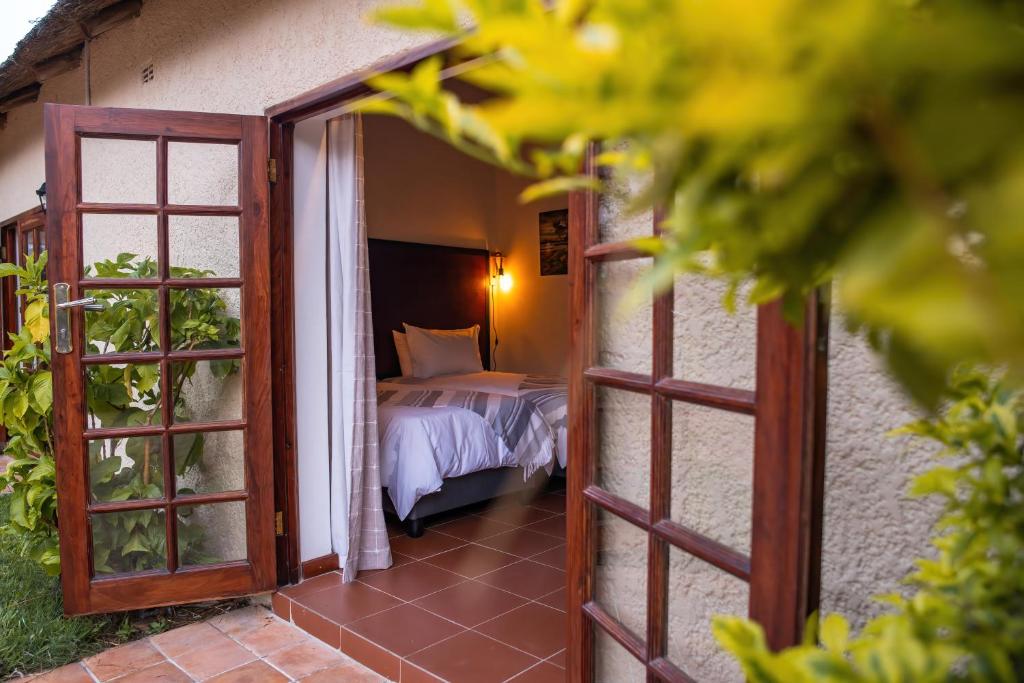 una puerta abierta a un dormitorio con cama en The Little Outlook en Victoria Falls
