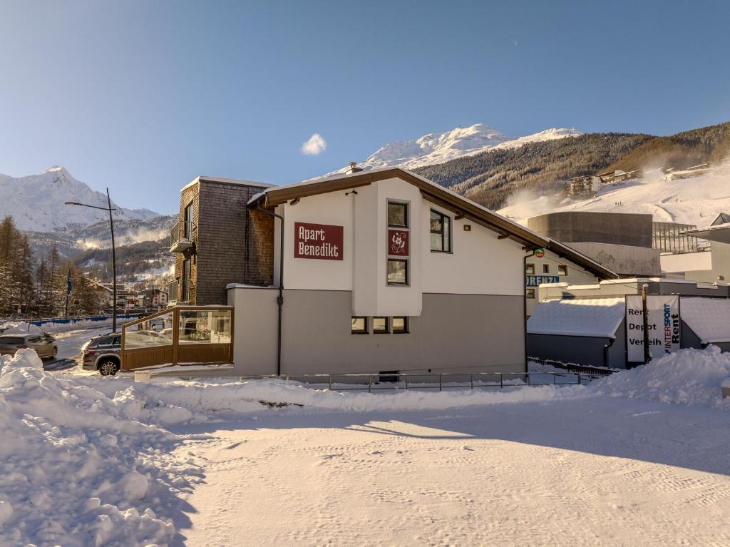 a building in the snow with mountains in the background at Apart Benedikt in Sölden