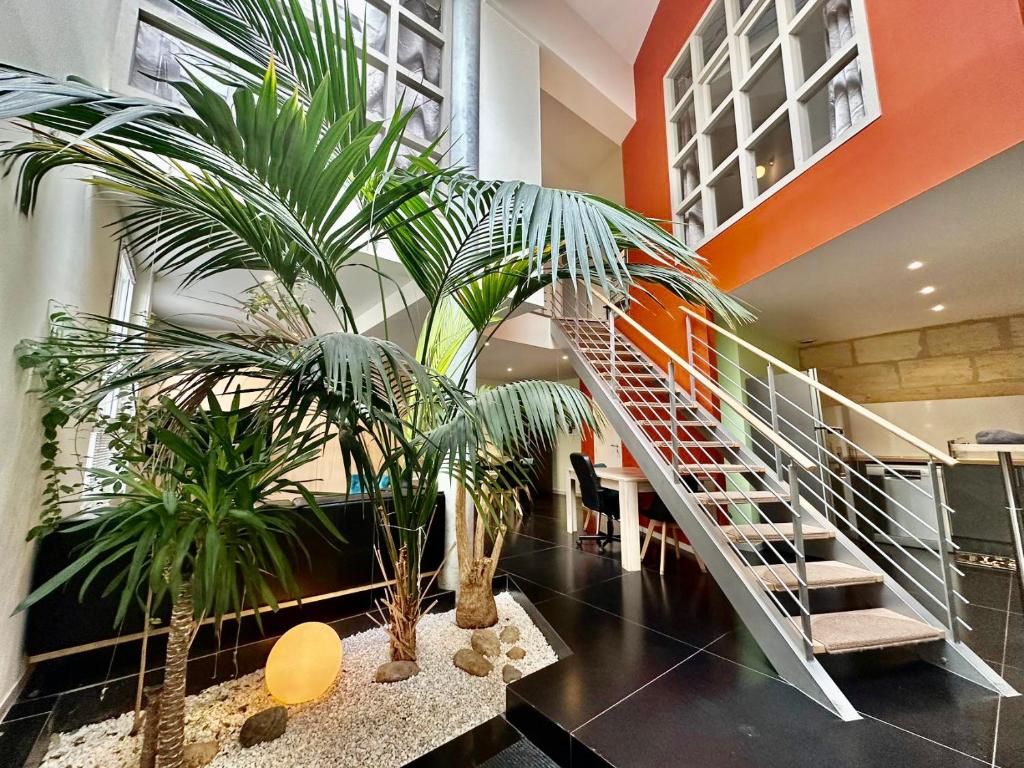a lobby with two palm trees and a staircase at Maison Stylée 98m2 centre bordeaux in Bordeaux