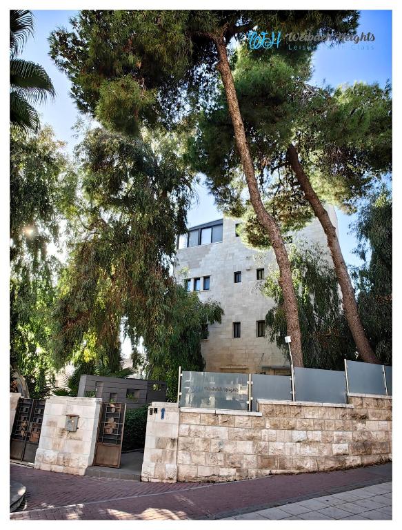 a building with trees in front of a stone wall at Weibdeh Heights Apartments in Amman