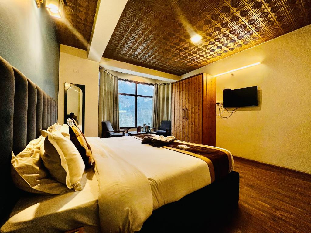 een slaapkamer met een groot bed en een televisie bij White Rose Hotel in Manāli