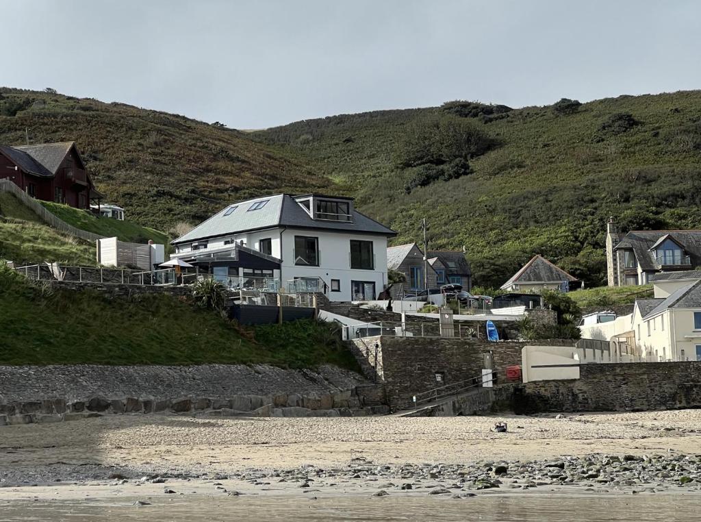a white house on a hill next to the beach at UPPER BEACH HOUSE in Portreath
