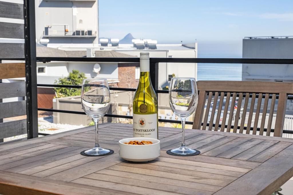 een fles wijn en twee glazen op een tafel bij Manhattan on Coral 7 in Bloubergstrand