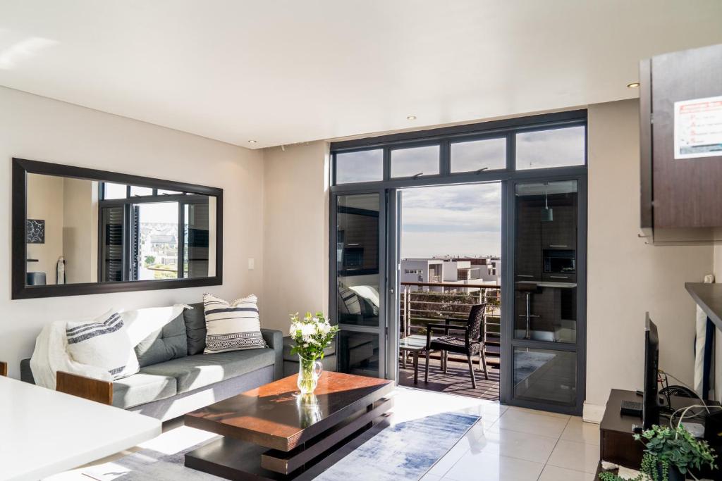 een woonkamer met een bank en een tafel bij Eden on the Bay Luxury Apartments, Blouberg, Cape Town in Bloubergstrand