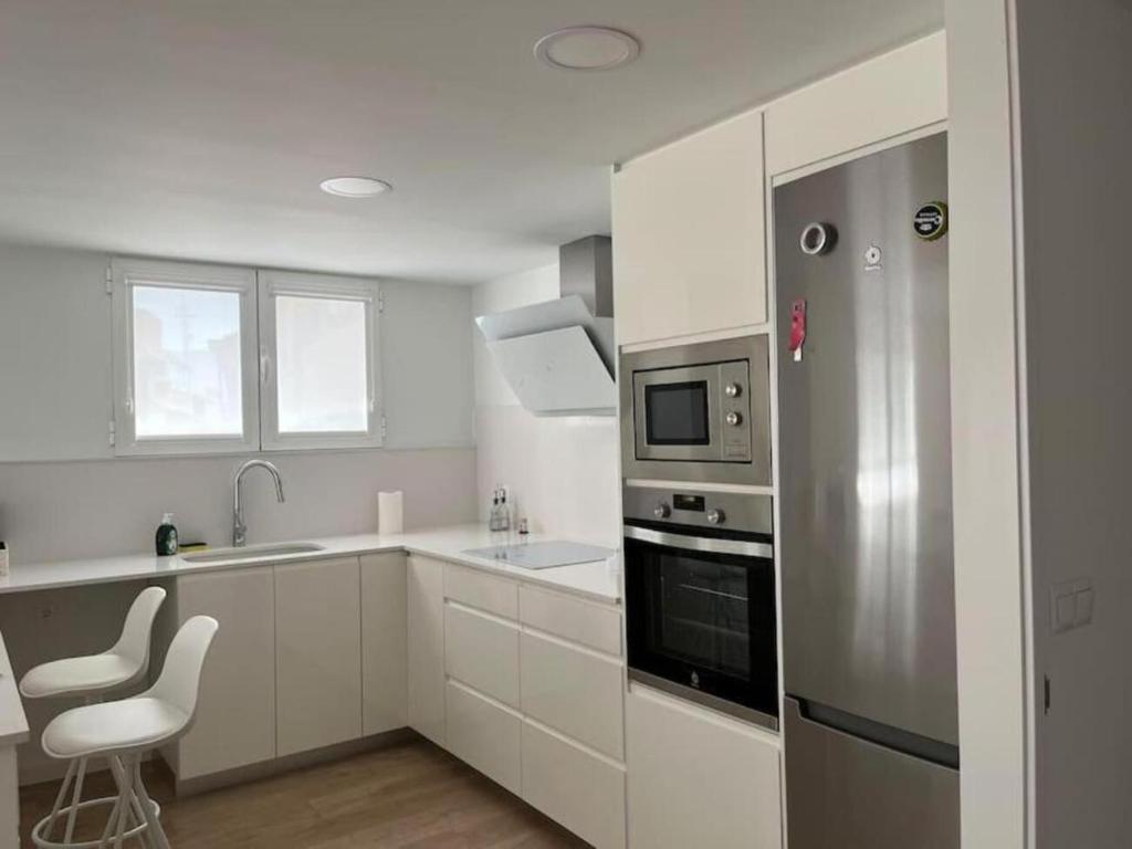 a kitchen with white cabinets and a stainless steel refrigerator at Carbo Home y Garaje , Algemesí Home in Algemesí