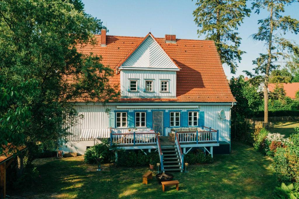 a white house with an orange roof and a yard at Pommernhaus Forsthaus Rieth am See, Sauna, Kamin, Ruderboot in Rieth