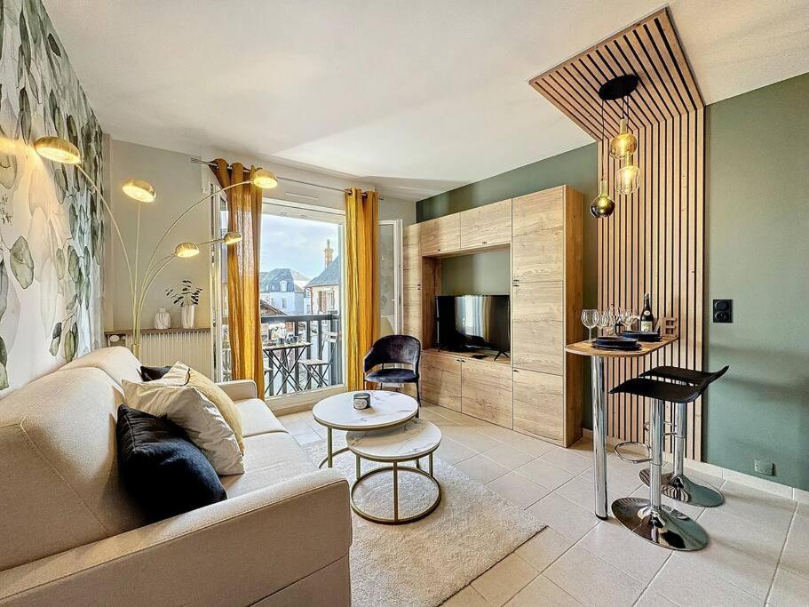 een woonkamer met een bank en een tafel bij Le Longchamp in Deauville