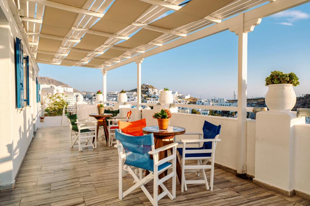 a balcony with tables and chairs and a view of the city at Palm in Ios Chora
