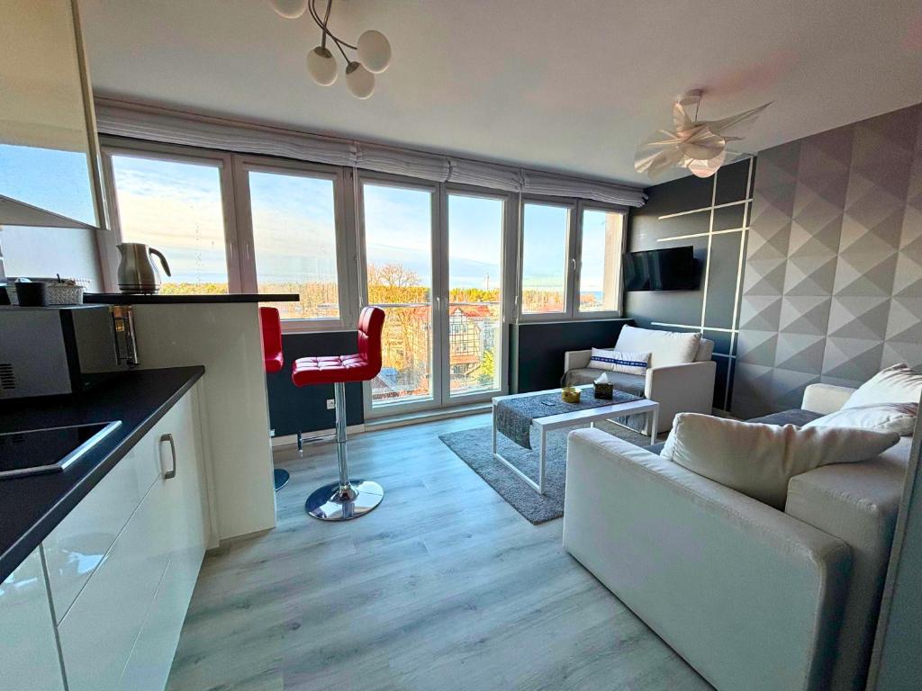 uma sala de estar com um sofá e uma cozinha com janelas em Apartament Everest by Managerent em Ustka