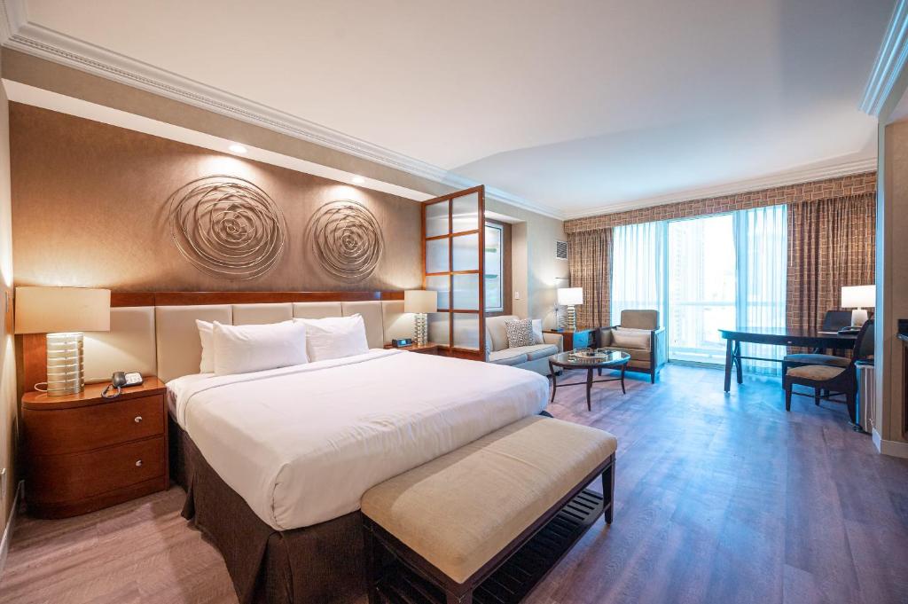 una camera d'albergo con un grande letto e una scrivania di No Resort Fee Strip View Balcony+ Valet Parking a Las Vegas