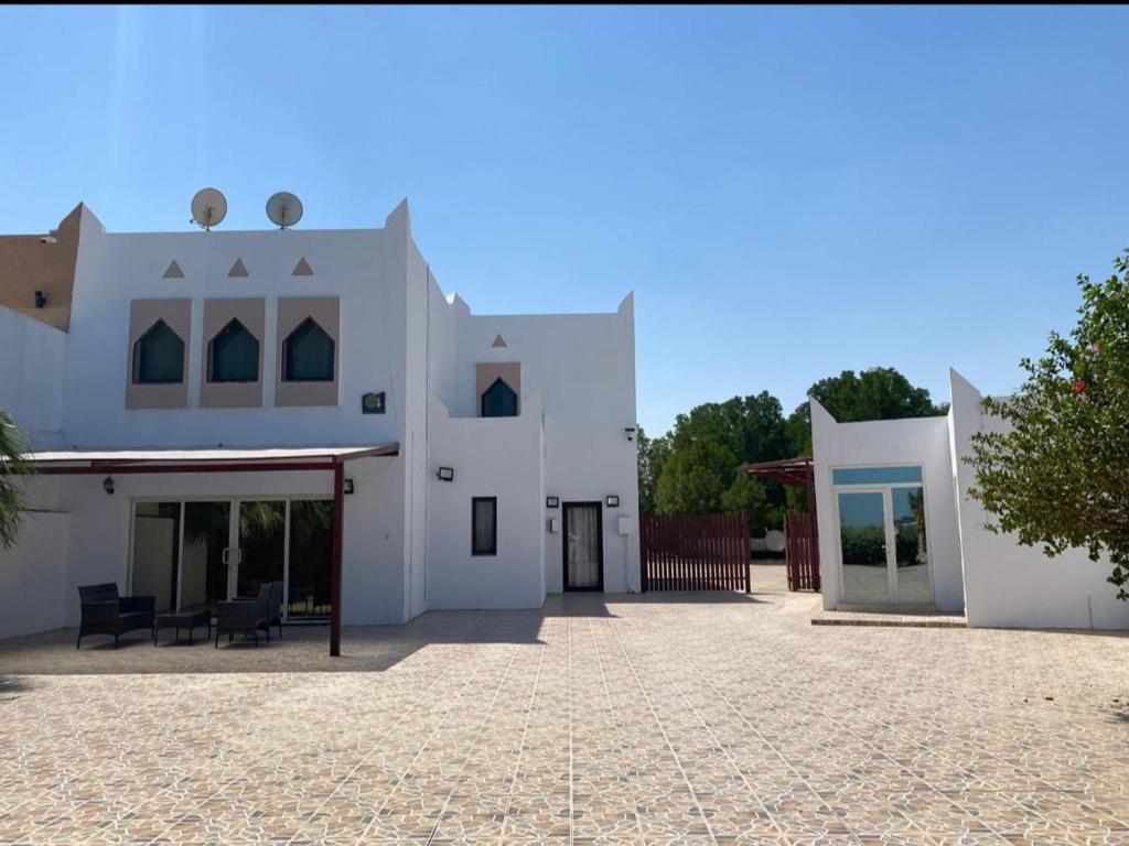 Una gran casa blanca con un patio en la parte delantera en Dana Beach Resort منتجع شاطئ الدانة, en Bahía de la Media Luna