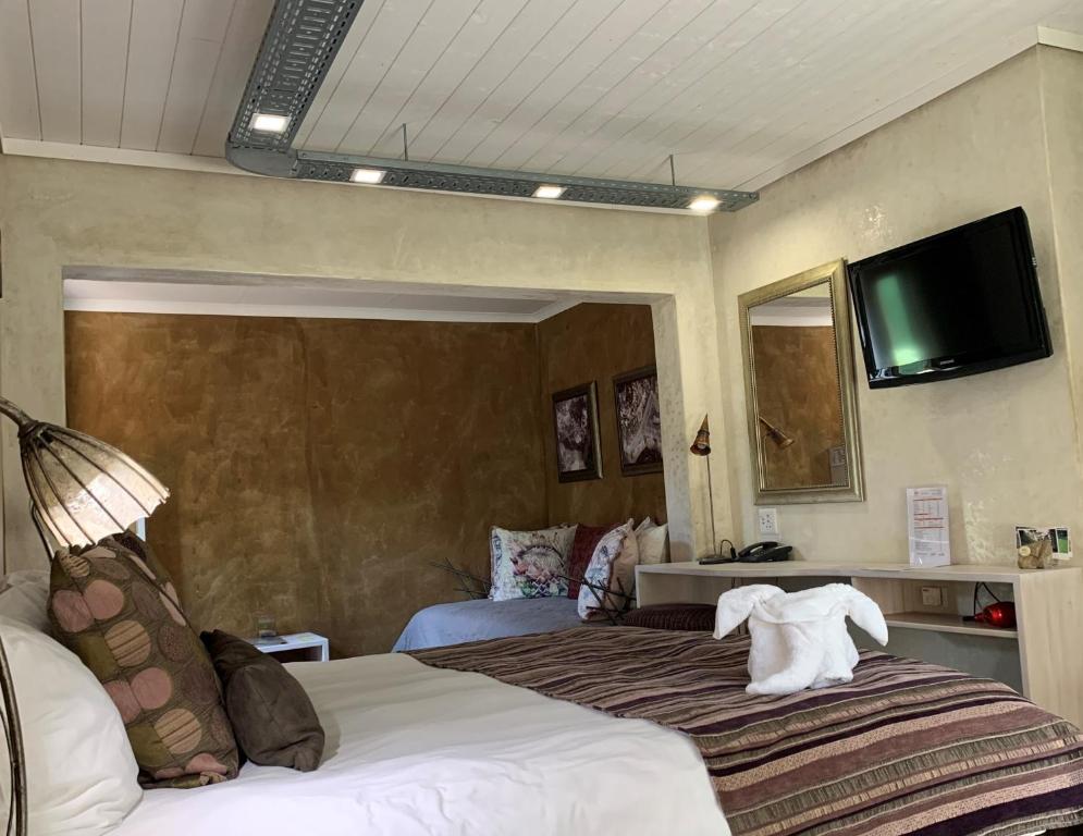ケンプトンパークにあるAfrican Rock Hotel and Spaのベッド1台、壁掛けテレビが備わるホテルルームです。