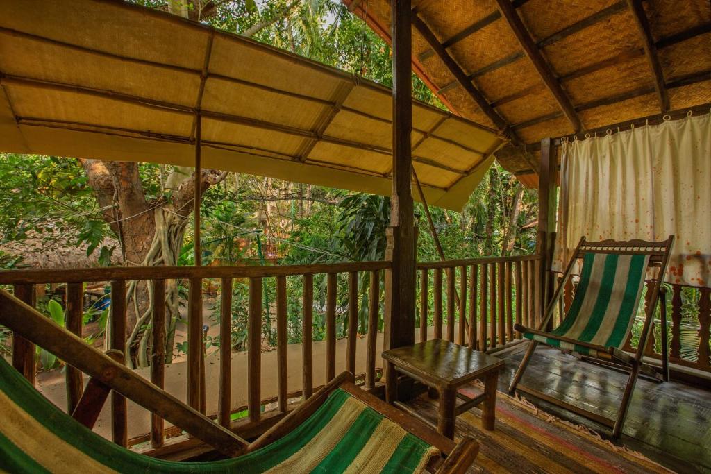 a porch with two chairs and a hammock at Bhakti Kutir in Palolem