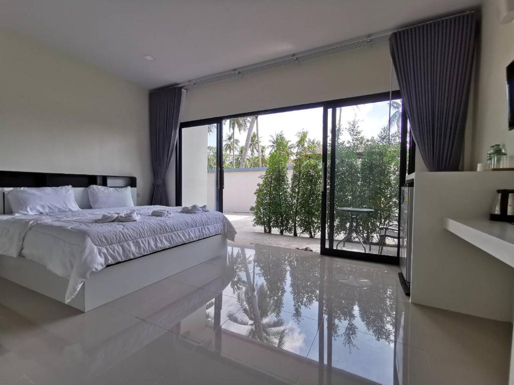 a bedroom with a bed and a large glass window at NST Boutique เอ็นเอสทีบูทีค in Ban Pak Phun