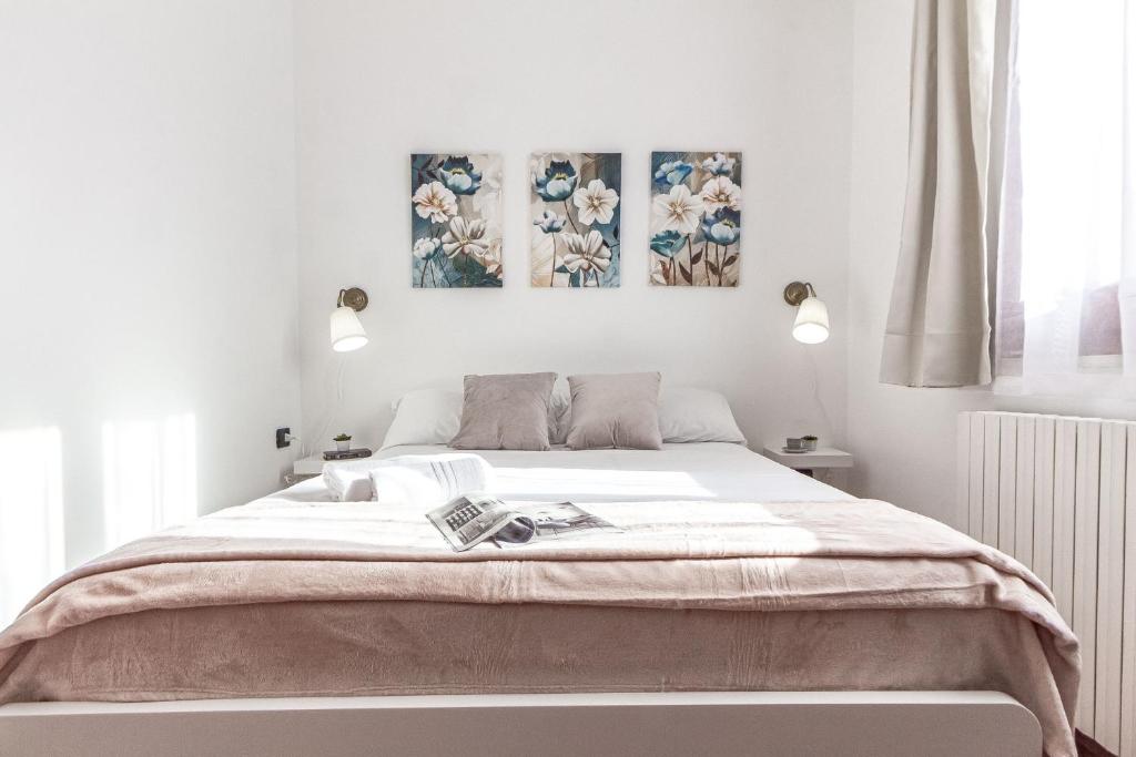 ein Schlafzimmer mit einem Bett mit drei Gemälden an der Wand in der Unterkunft Exclusive Roth Apartments in Sassari