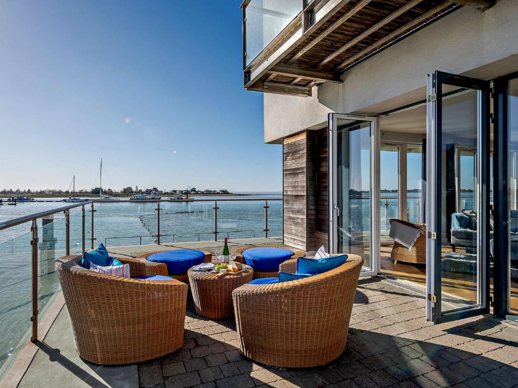 a patio with wicker chairs and tables next to the water at 2 Bed in Brightlingsea HARSI in Saint Osyth