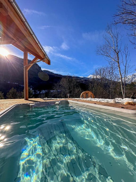 una piscina en una casa con una montaña en el fondo en Chalet ECRIN DES VIGNES en Les Vigneaux