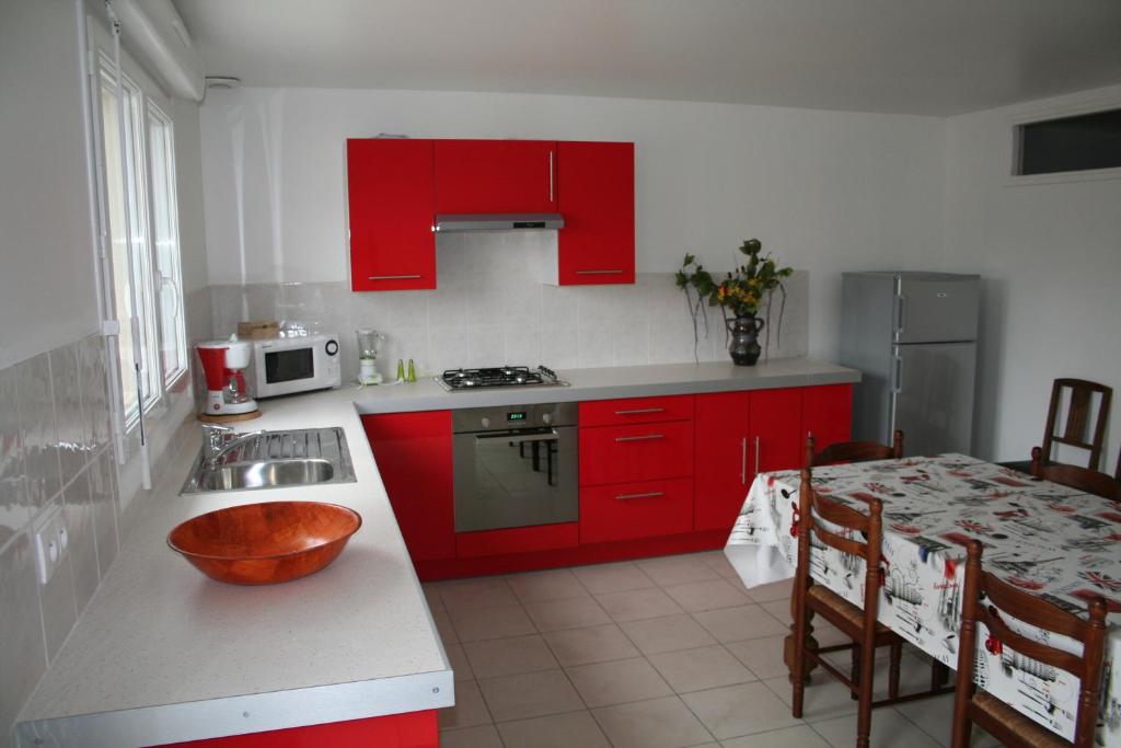 ウィッサンにあるLe gîte de Magalyの赤いキャビネットとテーブル(ボウル付)が備わるキッチン