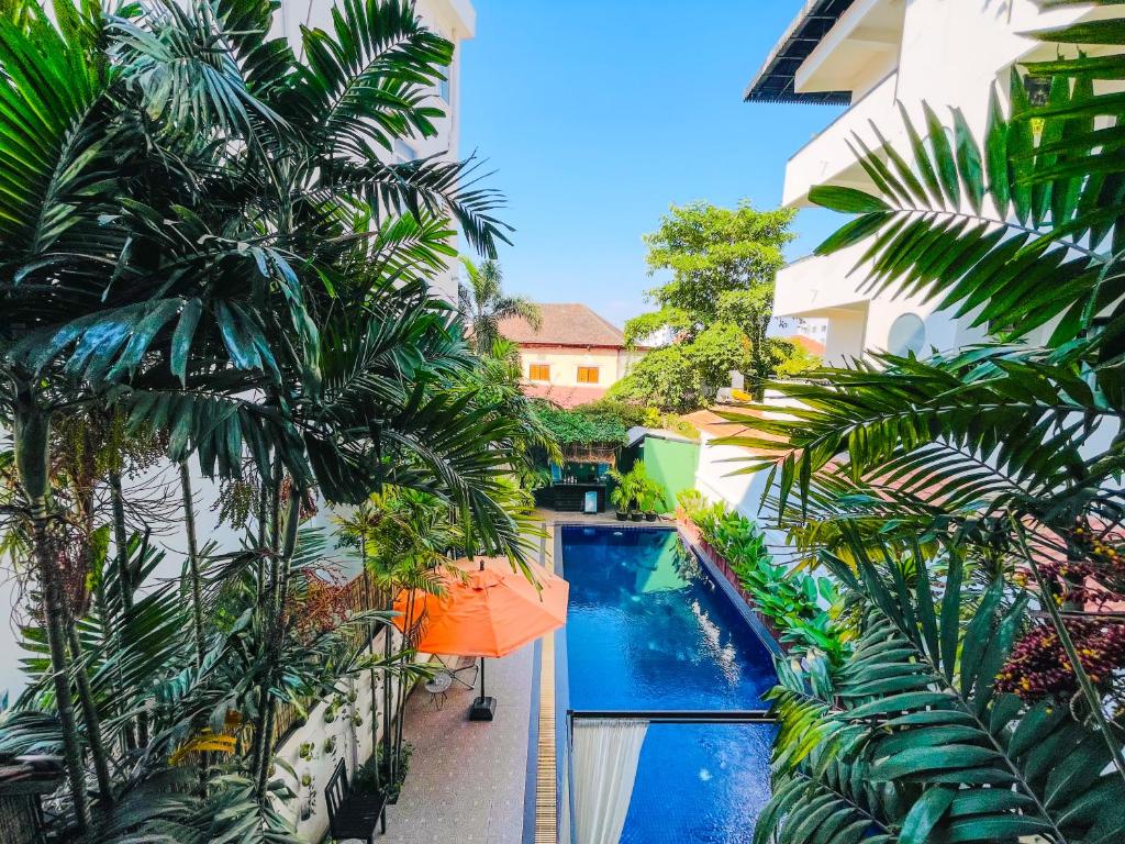 Blick auf einen Pool in einem Gebäude mit Palmen in der Unterkunft Siem Reap Urban Boutique Hotel in Siem Reap