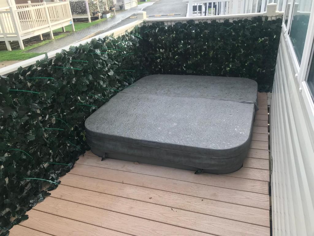 un matelas installé sur une terrasse couverte ornée de plantes dans l'établissement Hot Tub Accommodation Static North Wales, à Kinmel Bay