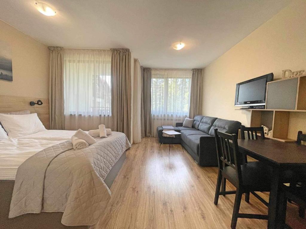 um quarto com uma cama, um sofá e uma mesa em Arboro Borovets Gardens E50 em Borovets