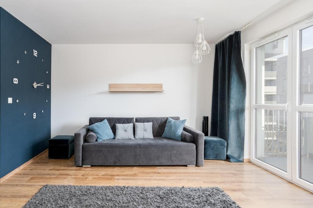 ein Wohnzimmer mit einem grauen Sofa und einem Fenster in der Unterkunft Prokocim Blue Studio in Krakau