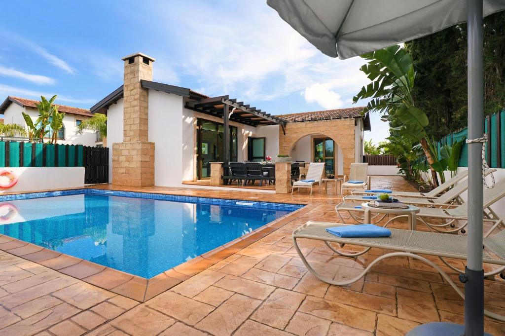 アヤナパにあるVilla Anthia - 2bed with Large Poolの家の隣にスイミングプール(椅子、パラソル付)