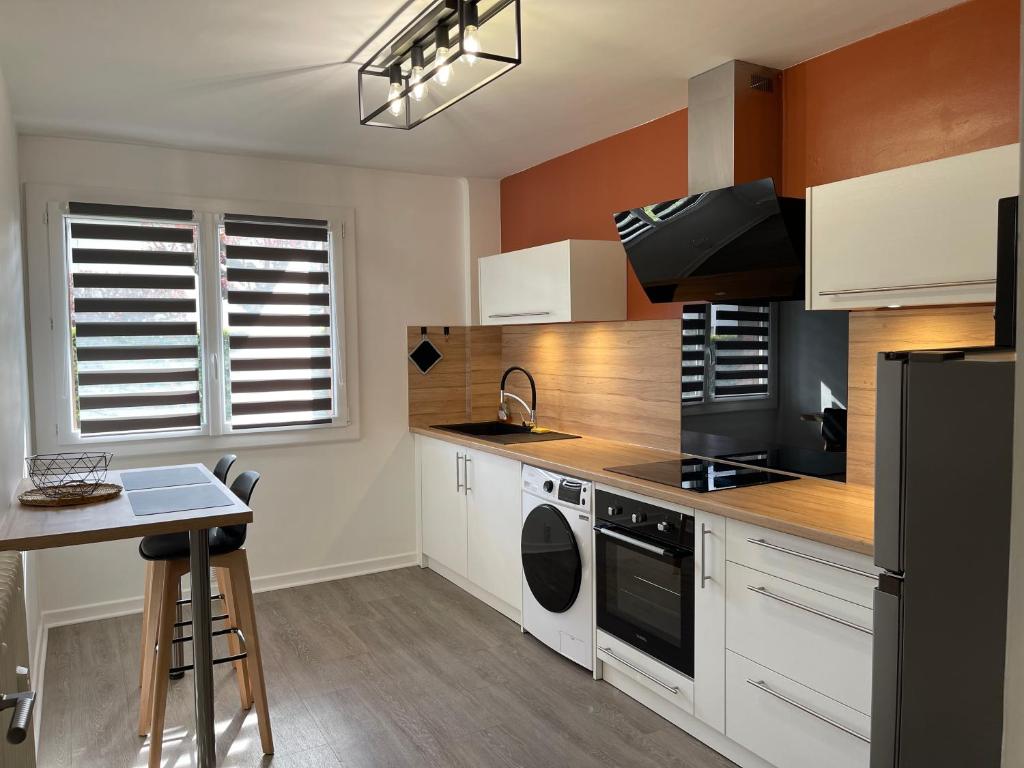 a kitchen with white cabinets and a stove top oven at Le Charmeur * * * in Aurillac