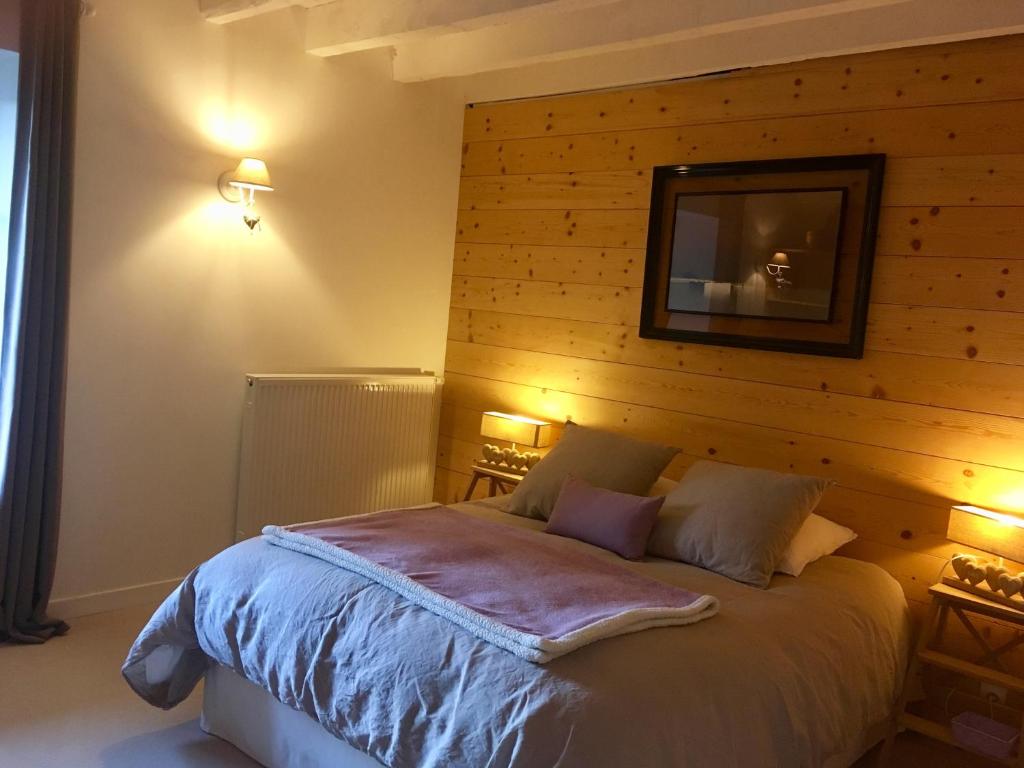 um quarto com uma cama e uma parede de madeira em La Colonie - Maison d'Hôtes em Collonges