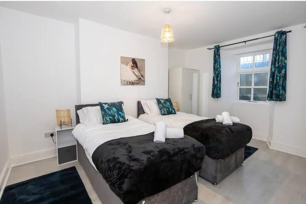 two twin beds in a bedroom with blue curtains at Devonshire Road - Apartment 1 in Birkenhead