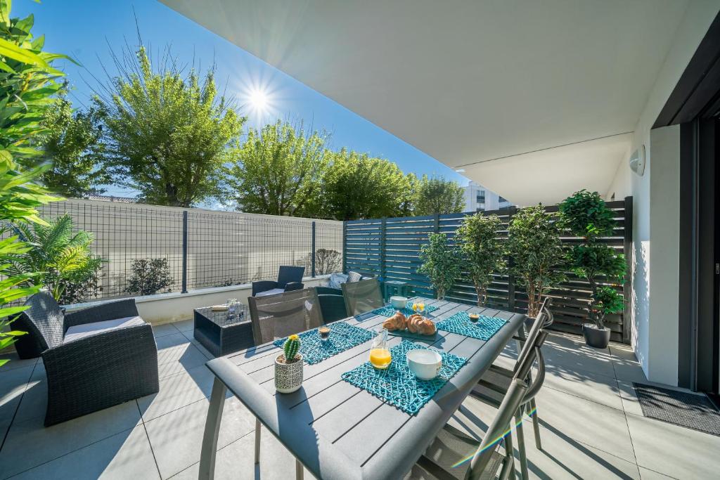 un patio avec une table et des chaises sur un balcon dans l'établissement La Pépite - Appt en Hypercentre au calme, Terrasse et Garage - Res Meyer, à Royan