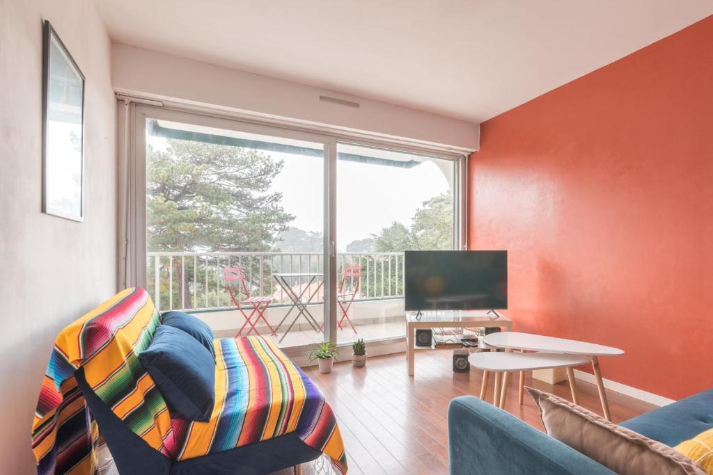 salon z kanapą, telewizorem i oknem w obiekcie Appartement à 200m de ThalassoSpa w mieście Pornic