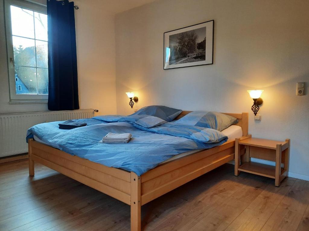 1 dormitorio con cama con sábanas azules y ventana en Pension am Bach, en Stützerbach