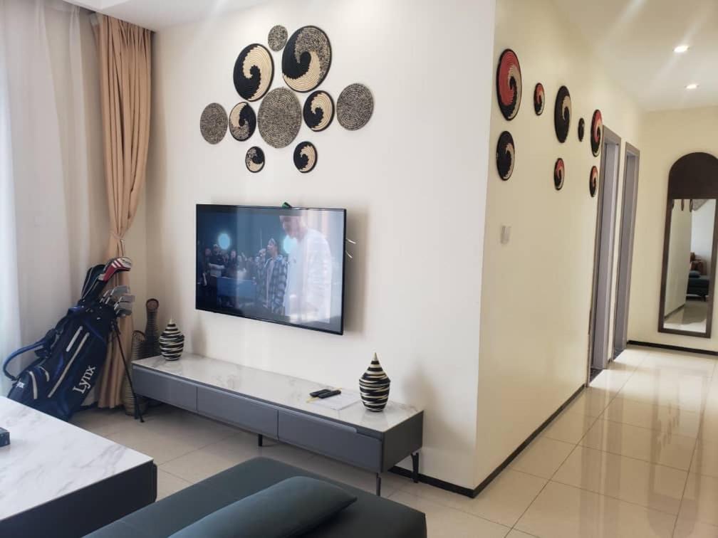 a living room with a flat screen tv on a wall at GolfHill Apartment in Kigali