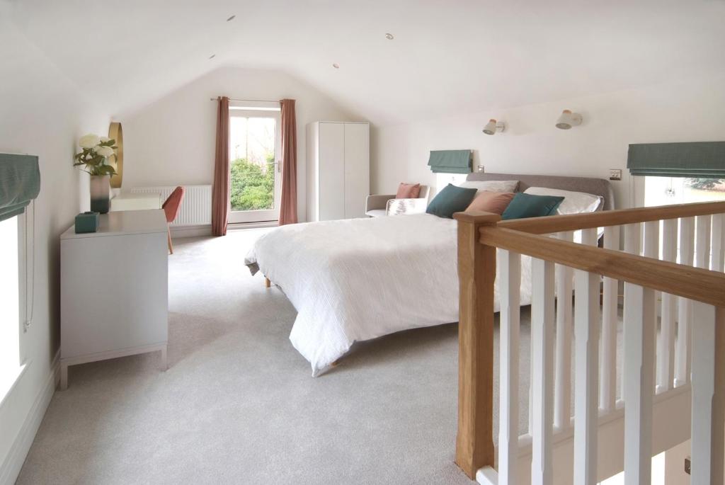a white bedroom with a bed and a staircase at Beautiful barn conversion with easy access to York in Selby
