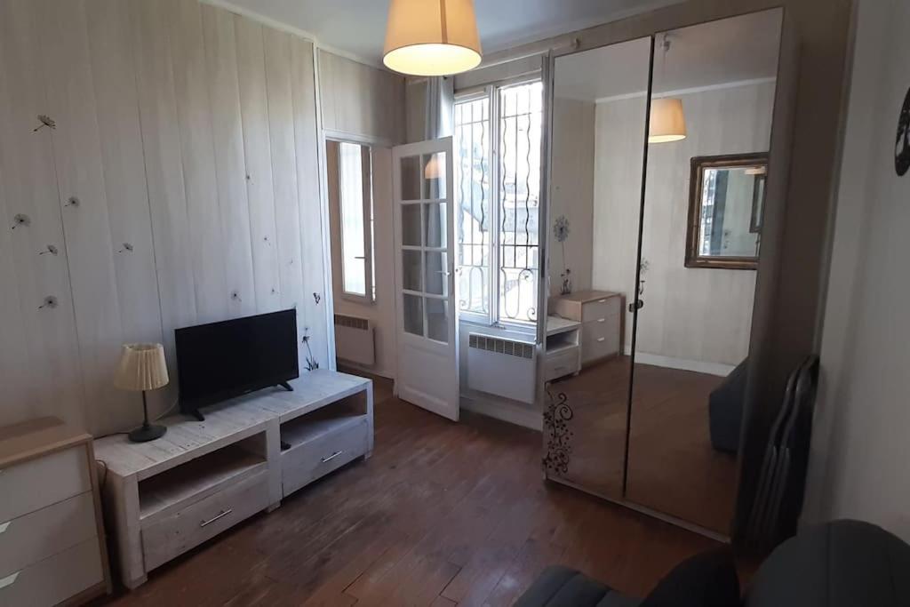 una sala de estar con un televisor de pantalla plana sobre un mueble en Calme, proche de Paris/ parc des princes, en Boulogne-Billancourt