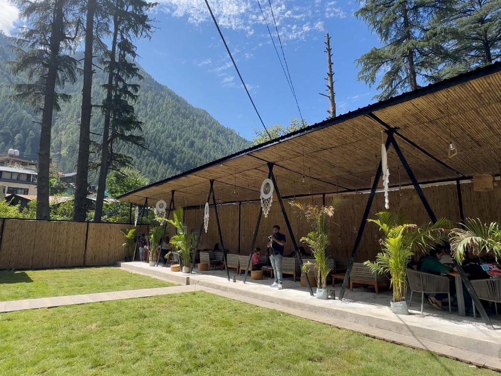 a tent with people sitting in it with mountains in the background at Pinewood by Offlimits Homes in Kasol