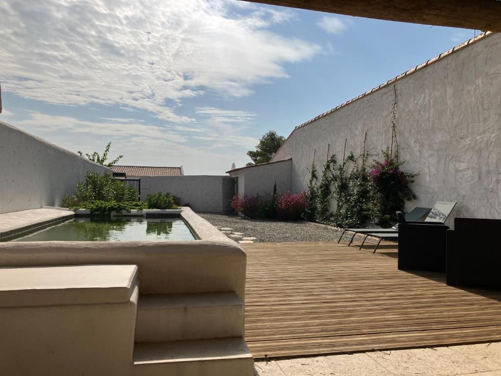 une arrière-cour avec une piscine et une terrasse en bois dans l'établissement Maison en Camargue Les Saintes-Maries de la mer, à Maguelonne-la-Sauvage