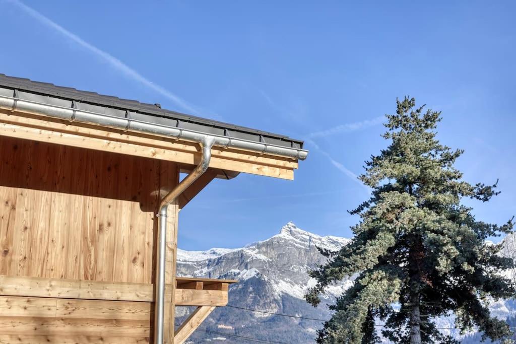 budynek z drzewem przed górą w obiekcie chalet Louis situé 25 km Chamonix w mieście Saint-Gervais-les-Bains
