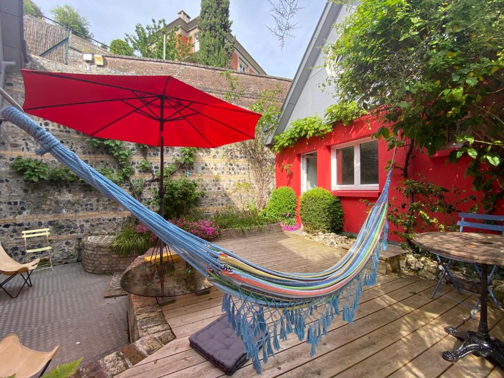 a hammock with a red umbrella on a patio at charmante maisonnette in Le Havre