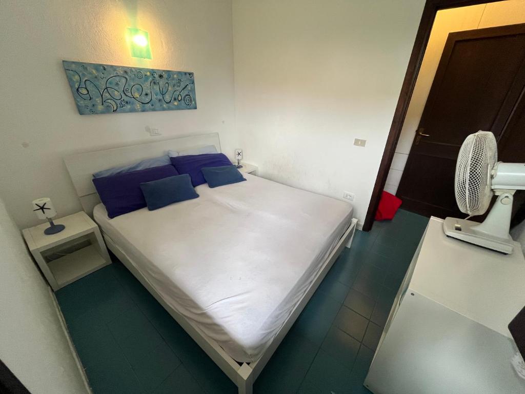 カンニジョネにあるBilocali Residenza Mediterranea Cannigioneの小さなベッドルーム(白いベッド、青い枕付)