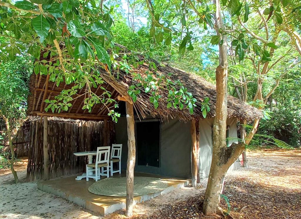 Cabaña pequeña con mesa y sillas frente a ella en Bamba Kofi Tented Camp, en Watamu