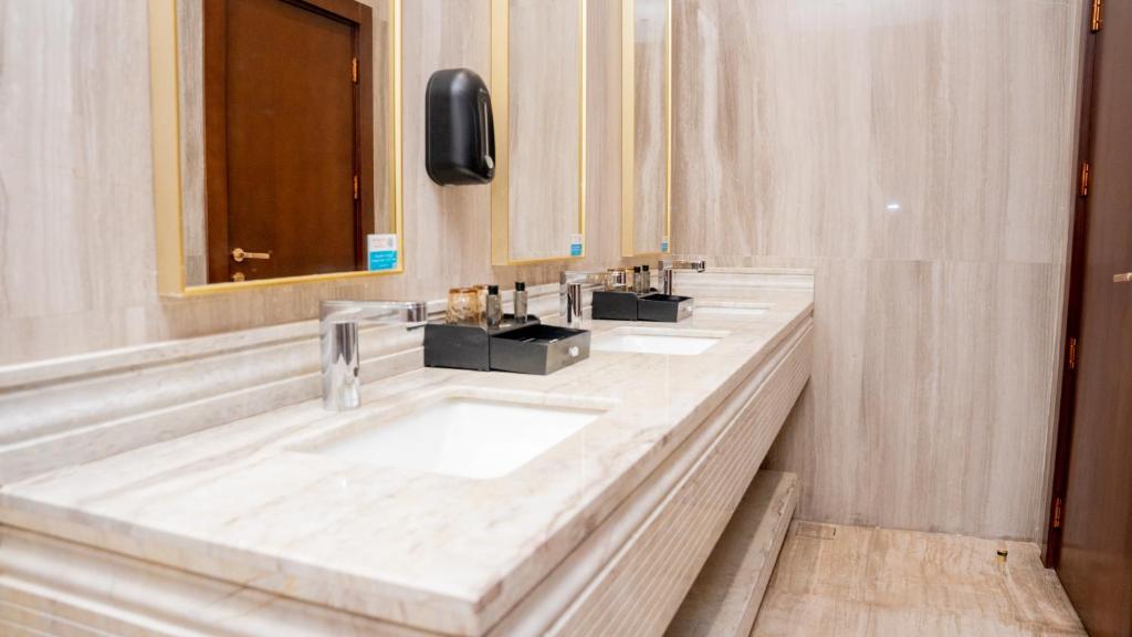 een badkamer met 3 wastafels en een spiegel bij Rose Bark - روز بارك in Hafr Al Baten