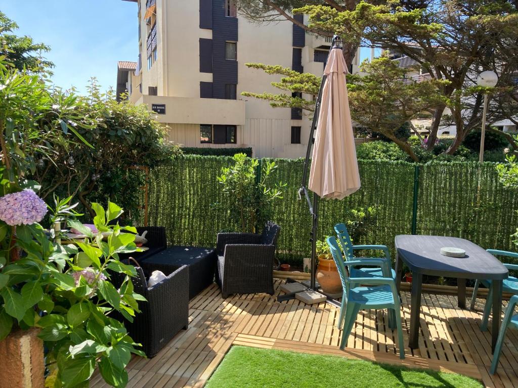 un patio avec une table, un parasol et des chaises dans l'établissement Appartement cocooning à 200m des plages, à Seignosse