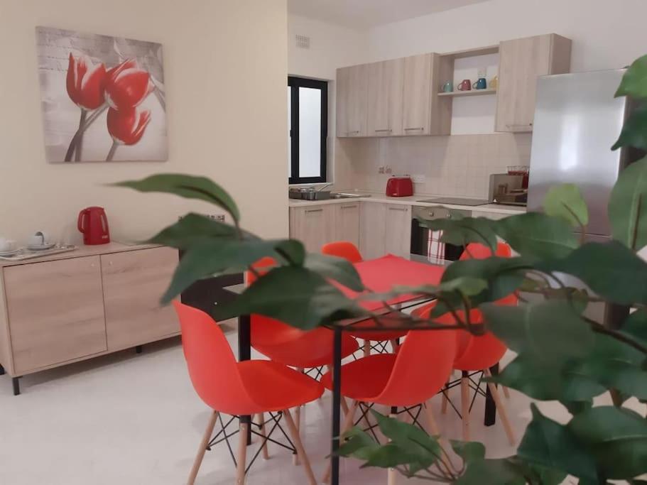 a kitchen with red chairs and a table at Xlendi Home in Xlendi