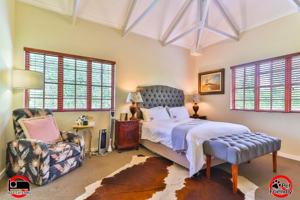 a bedroom with a bed and a chair and windows at Cinzaco Dullstroom in Dullstroom