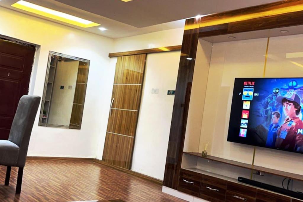 a room with a flat screen tv on a wall at Vim 2-BR-Apt With Fast Unlimited Internet & 24HRS Power in Lagos