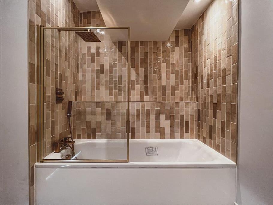 a bath tub in a bathroom with a tile wall at Home at Highgrove - Private Garden & Parking in Reading