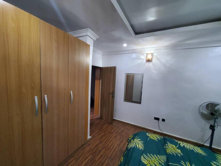 a bedroom with a bed and a wooden cabinet at Vim 2-BR-Apt With Fast Unlimited Internet & 24HRS Power in Lagos